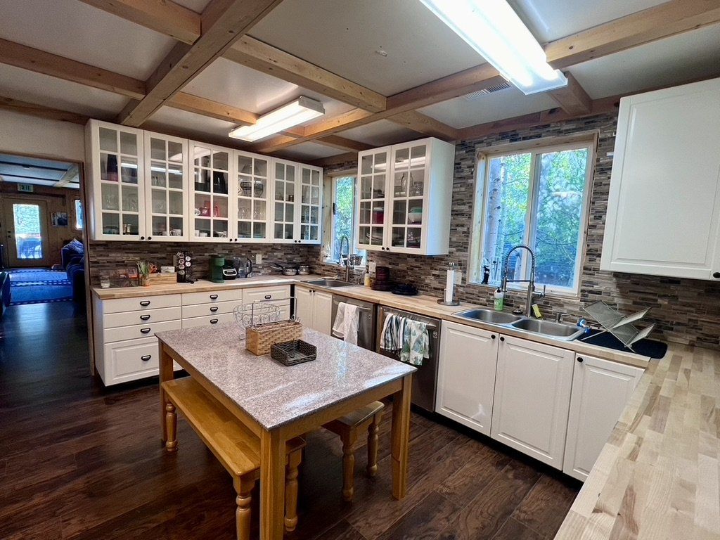 Large kitchen with white cabinets and a farmhouse table, at The Refuge at Lost Creek